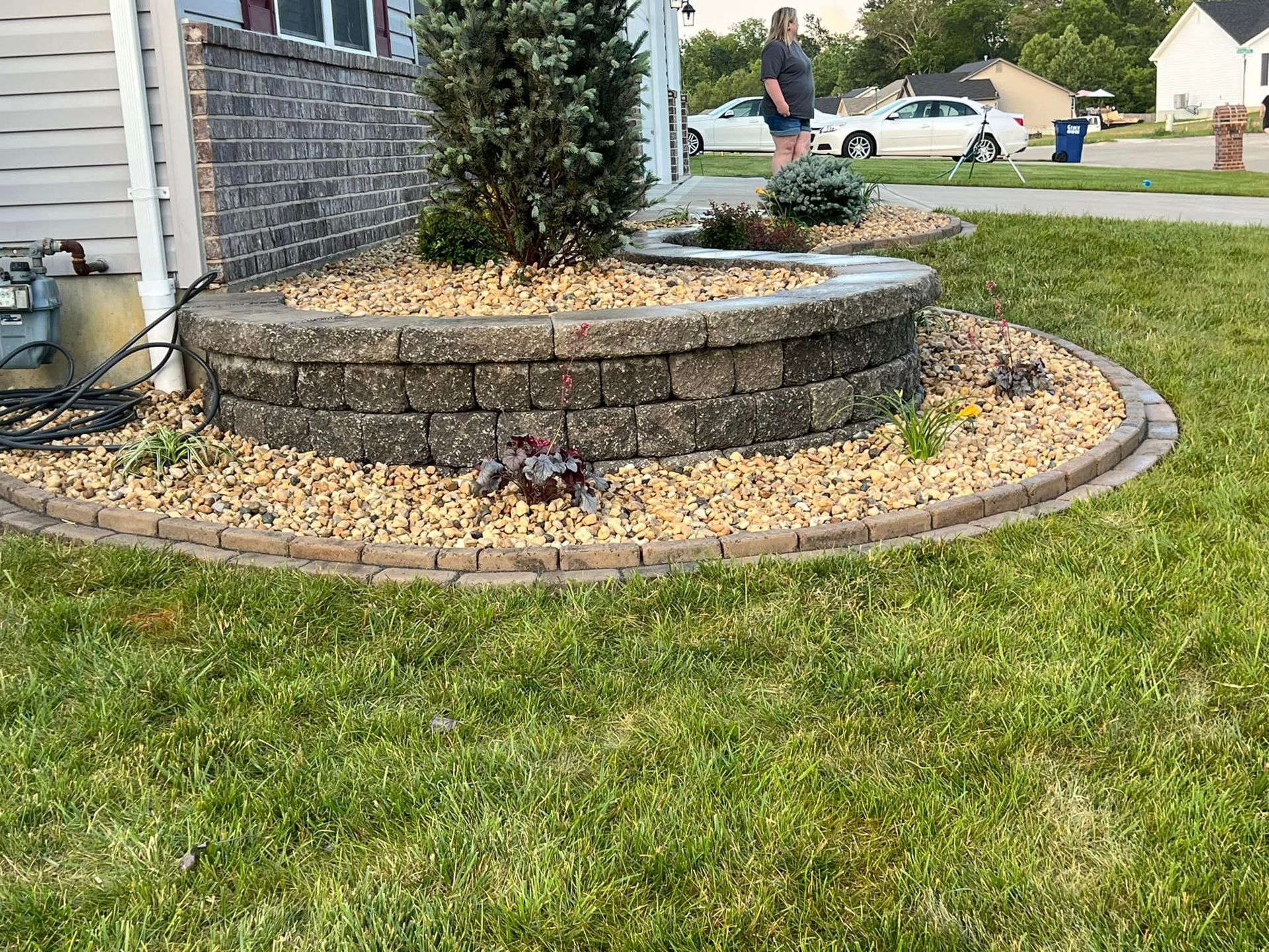 A Man Is Standing in Front of A House Next to A Brick Wall | O’Fallon, MO | Vickscapes Land Maintenance and Pools