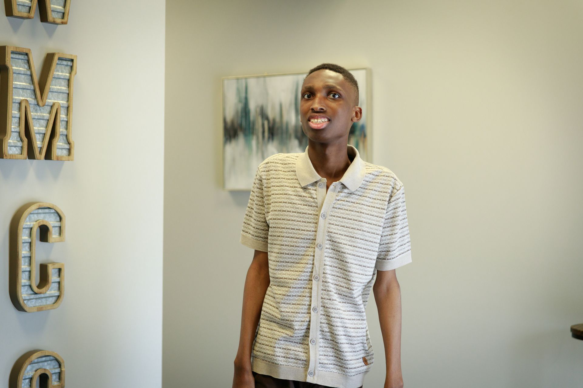 Special Needs Ministry Available A young man is standing in a room with a painting on the wall.