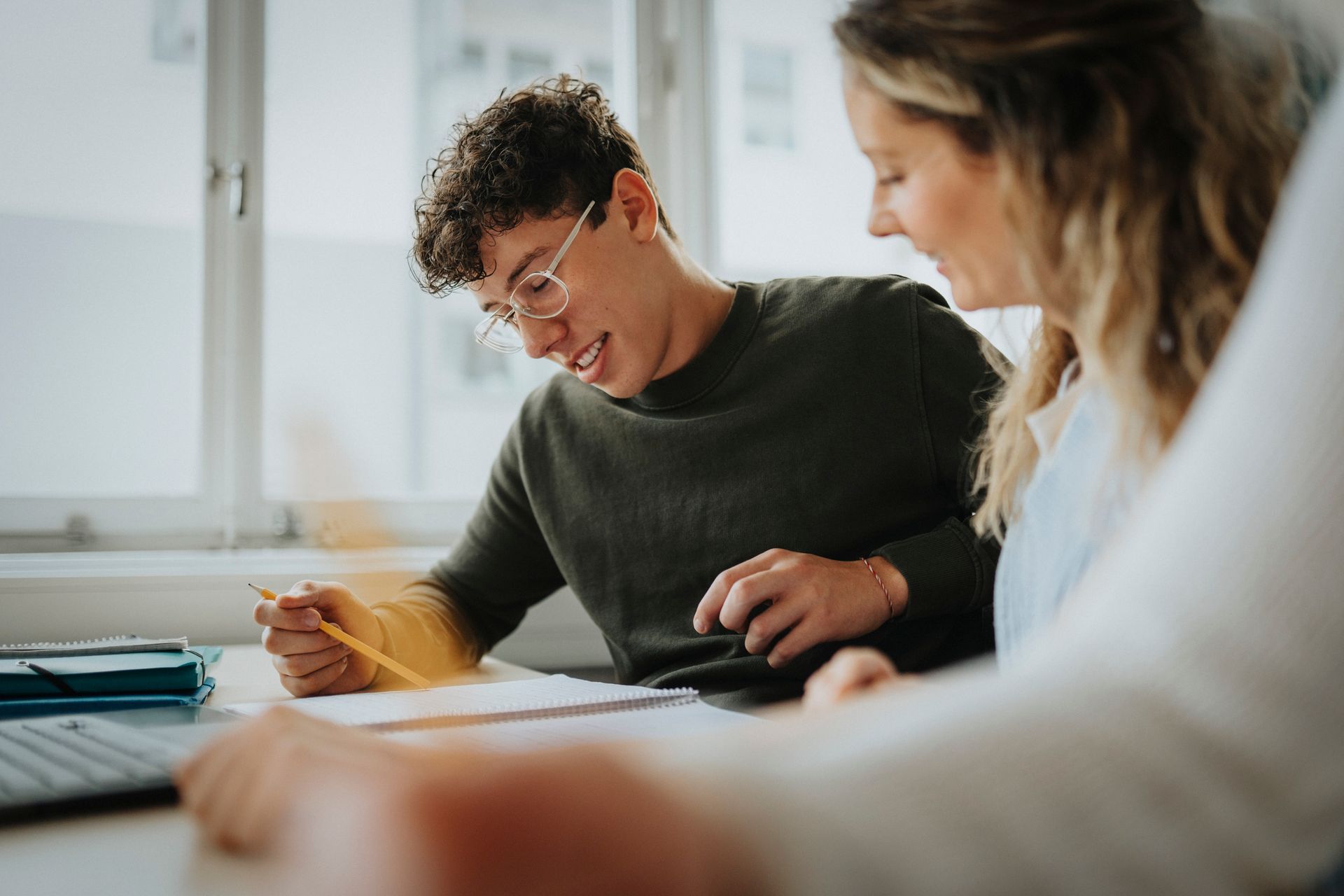A man is sitting on a bean bag chair reading a book to a group of children.