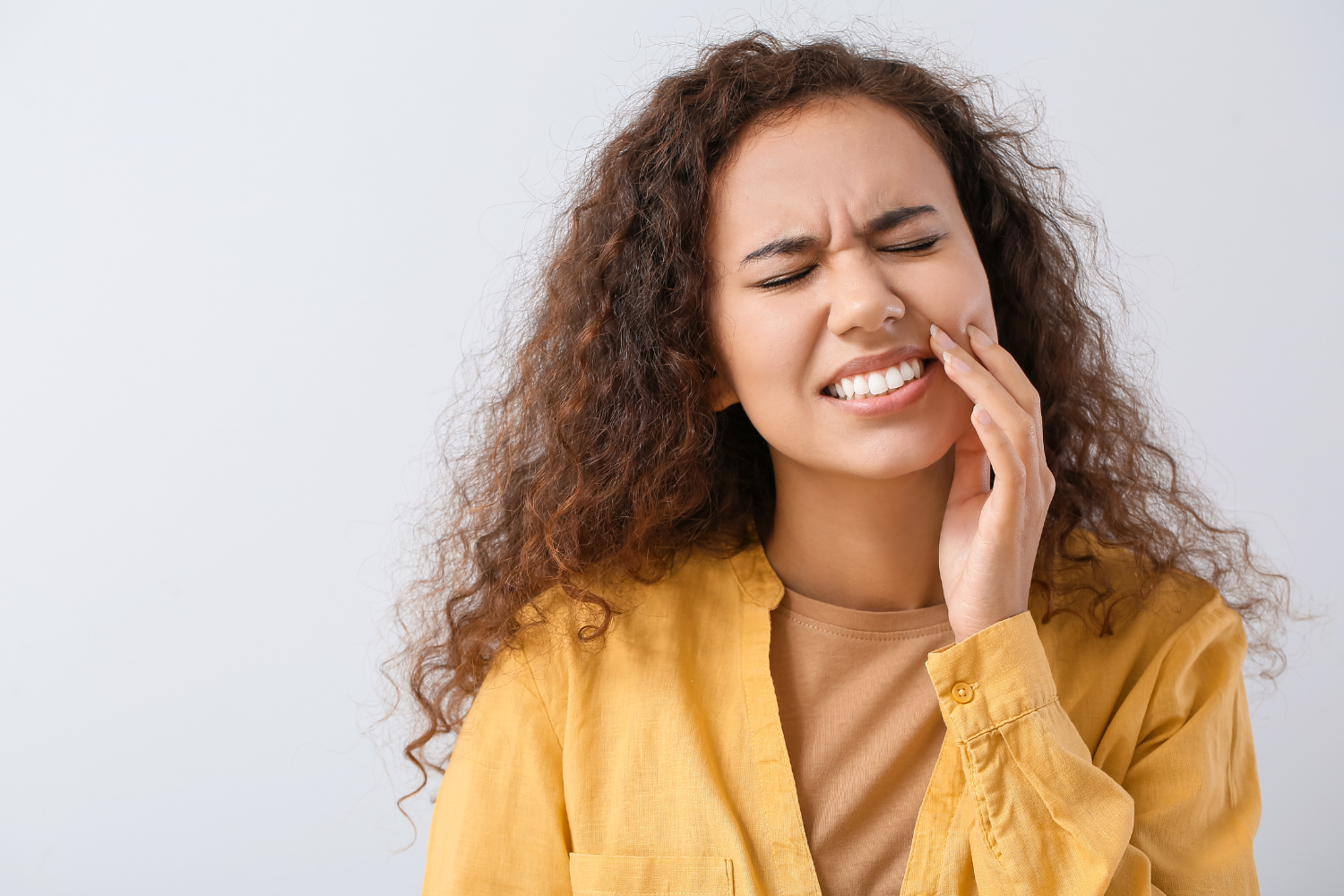 a woman in a yellow shirt has a toothache