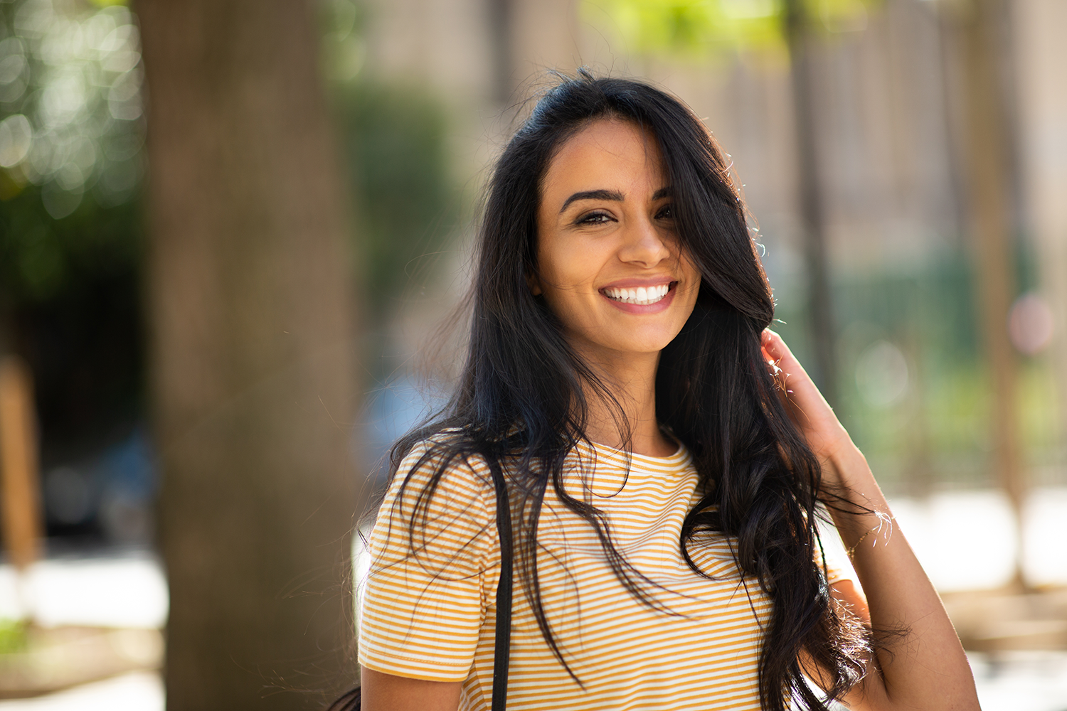 a woman in a yellow and white striped shirt is smiling