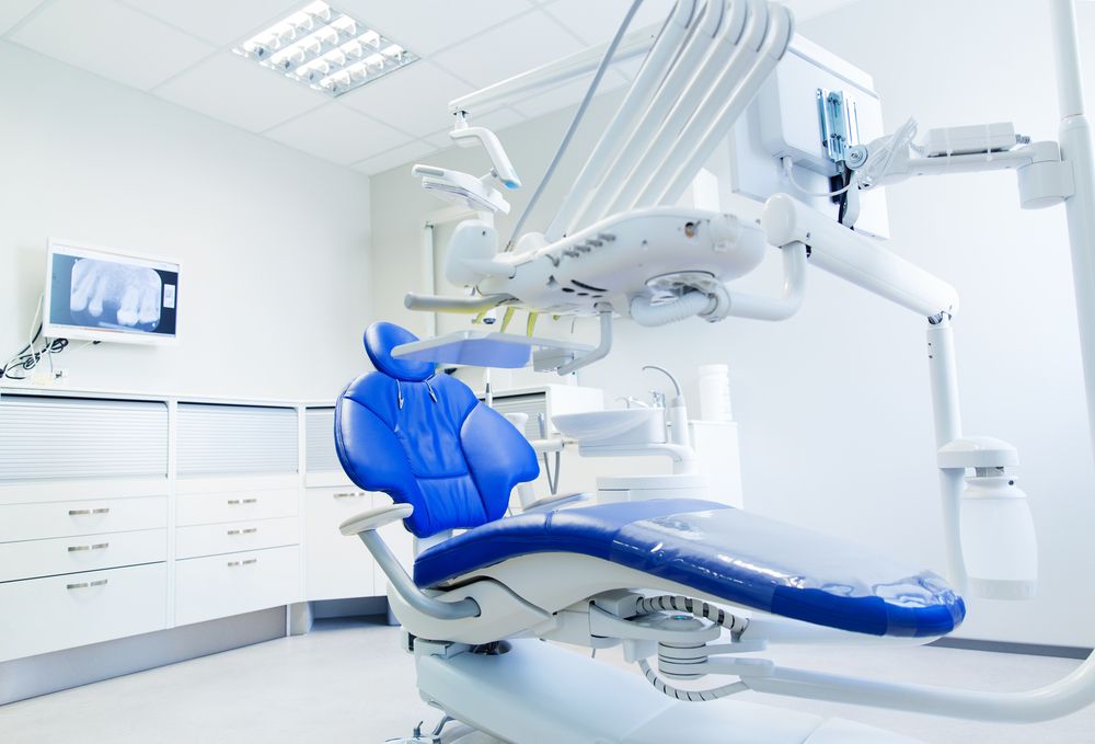 an empty modern dental office with a blue dental chair