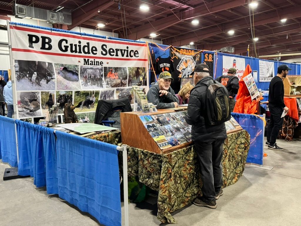 PB Guide Service booth at a fair with people looking at information and brochures.
