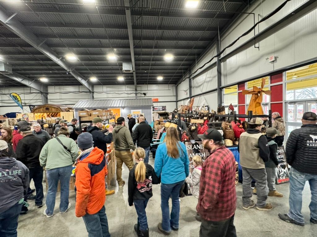 Large indoor event with many people browsing various displays.