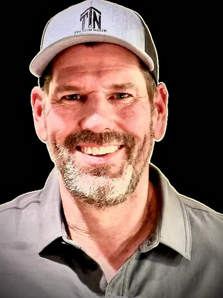 Man wearing a gray cap and shirt, smiling, with a beard.