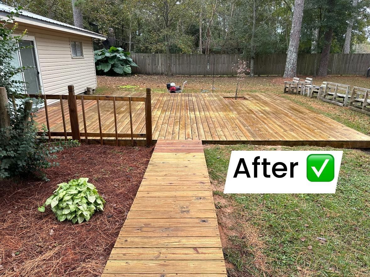 A wooden walkway leading to a backyard with a house in the background.