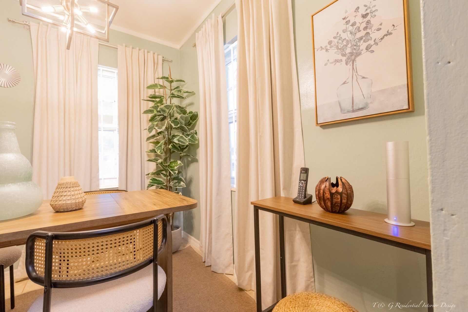 Modern dining room with black accent wall, abstract art, a long wooden table, and patterned rug.
