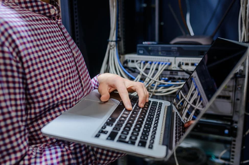 A Man Is Using A Laptop Computer In A Server Room — D-stress Computers In Idalia, QLD