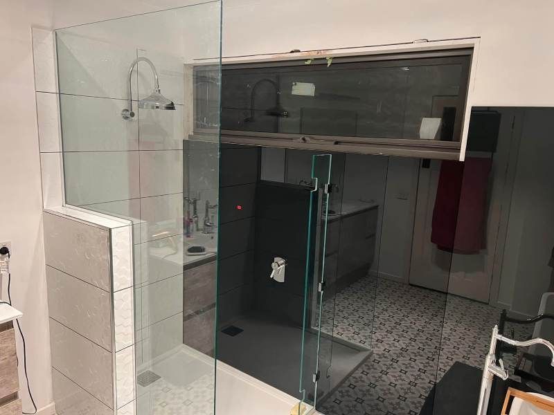Modern bathroom with glass shower enclosure, tiled walls, and a dark vanity cabinet