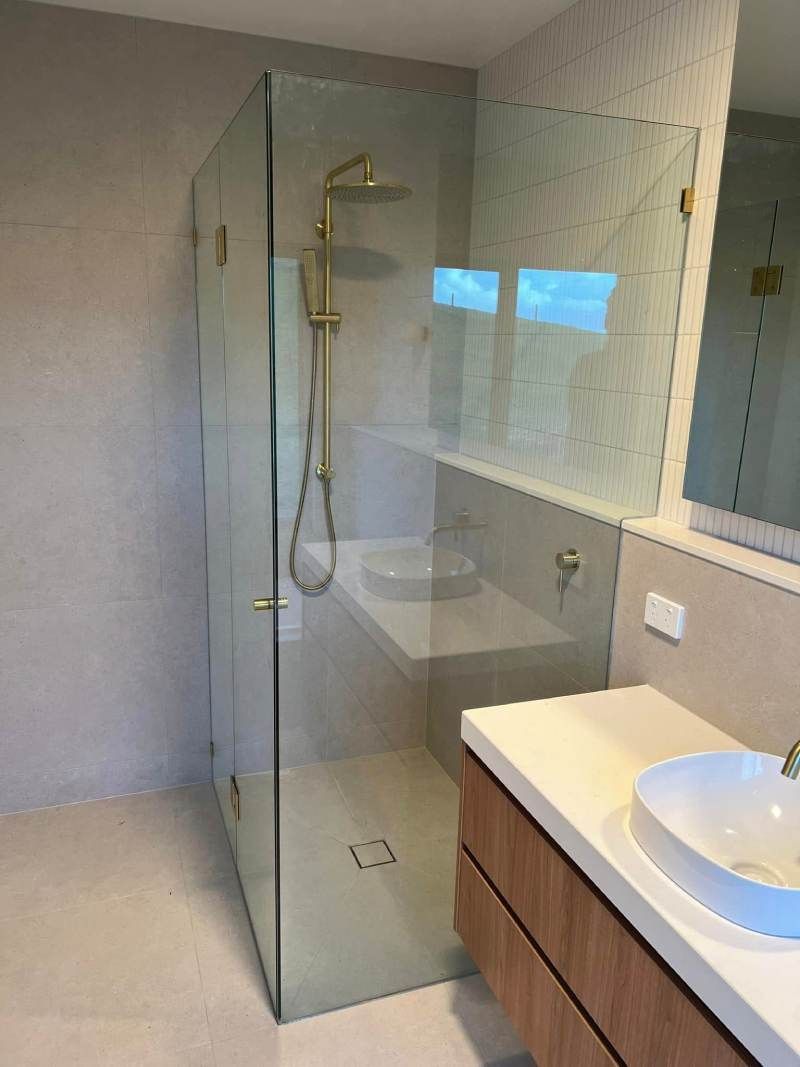 Modern bathroom with glass shower enclosure, vanity sink, and large mirror