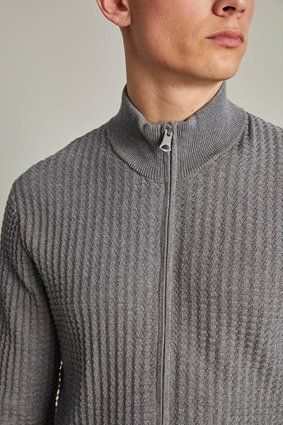 Man wearing a gray textured zip-up sweater.