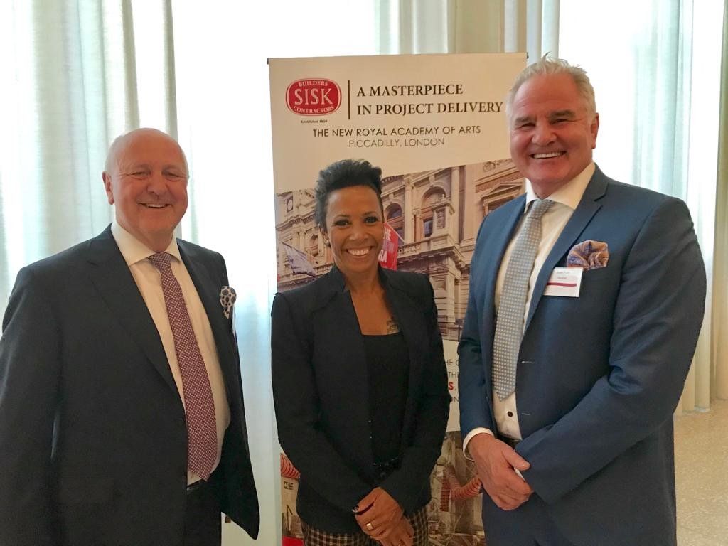 Three people posing near a banner that reads 