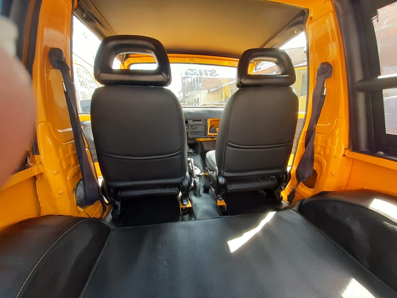 El interior de un coche amarillo con dos asientos negros.