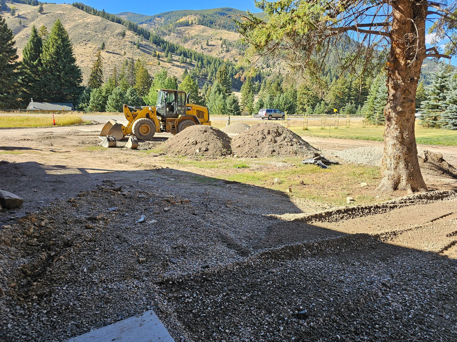 Two men are standing next to a bulldozer and an excavator in a field.