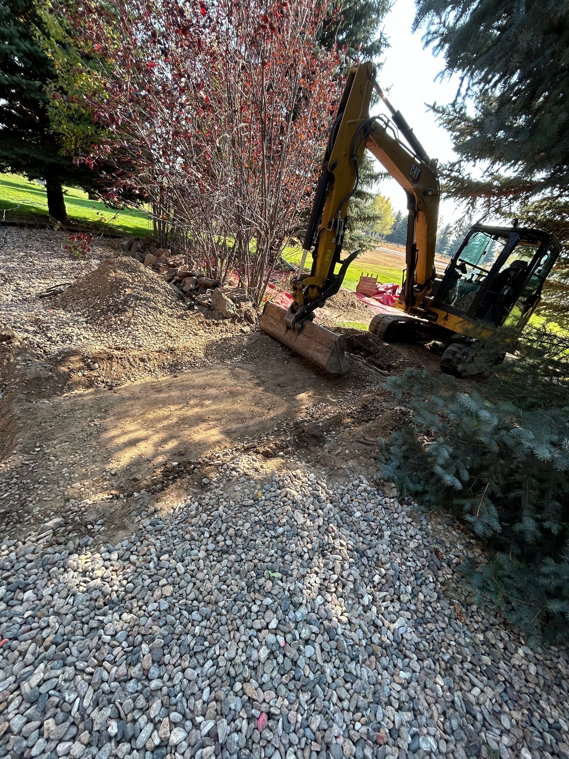 Two men are standing next to a bulldozer and an excavator in a field.