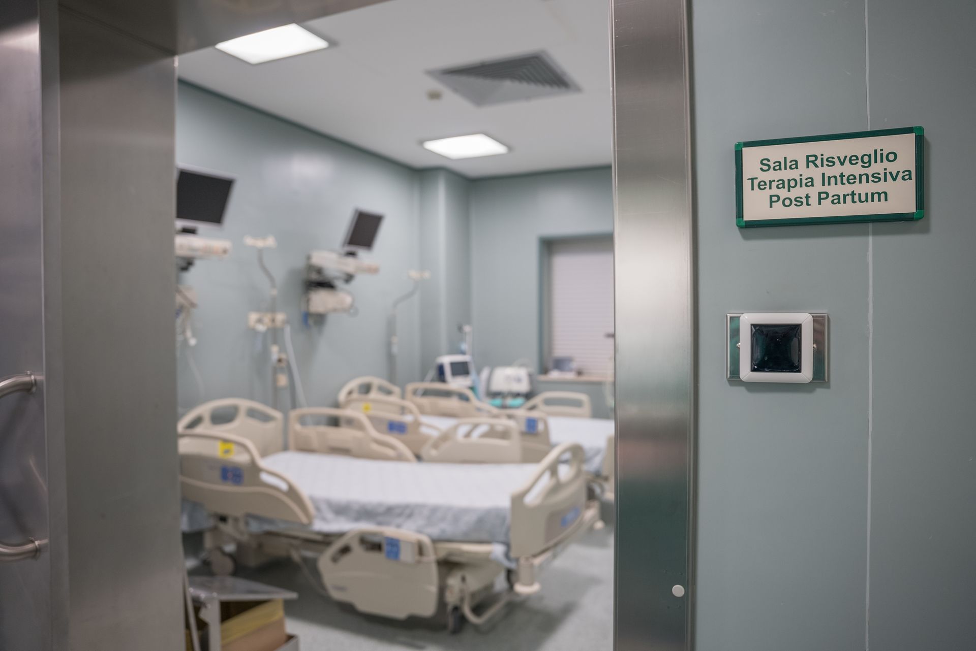 Una stanza d'ospedale con molti letti e un cartello sul muro.