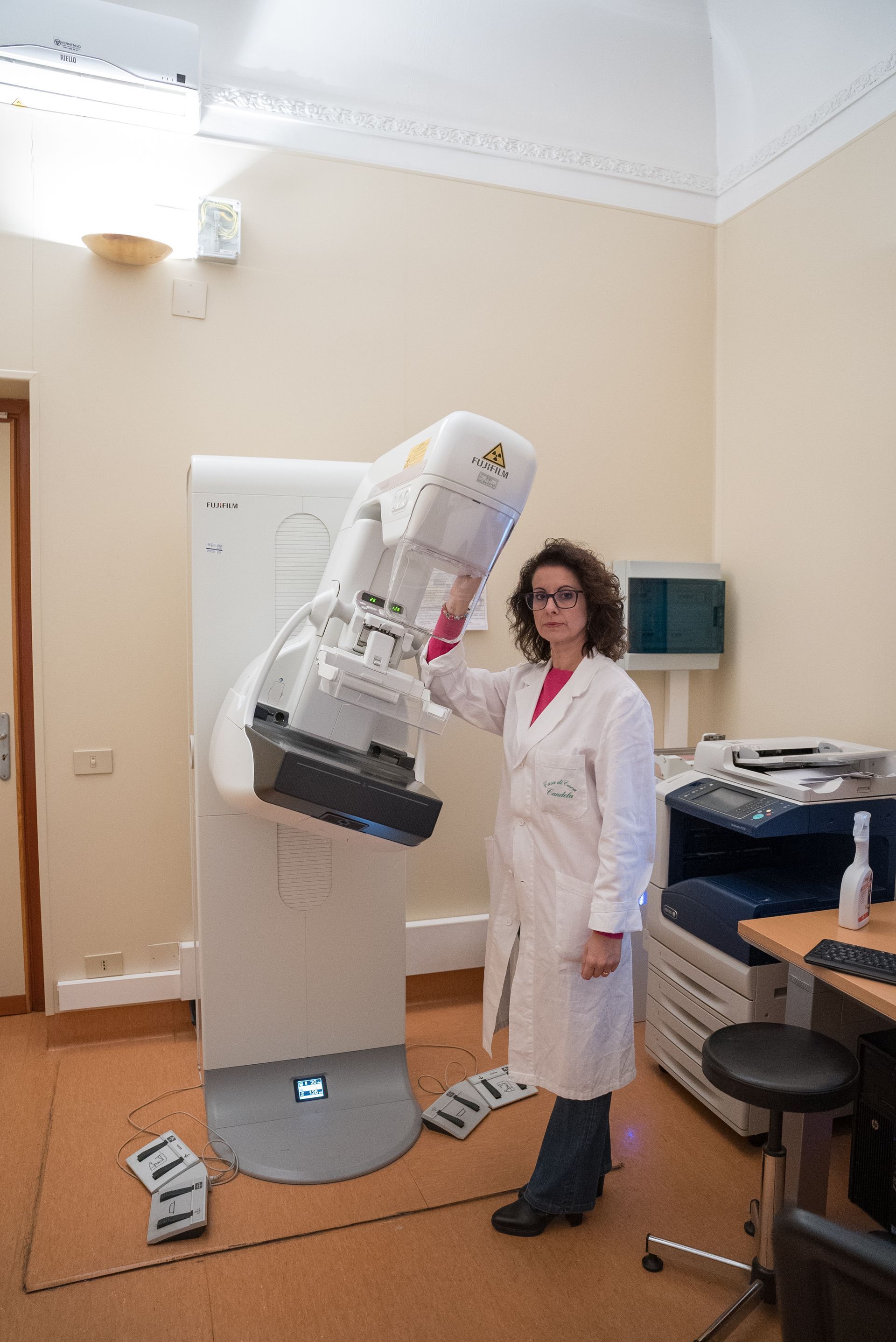 Una donna in camice è in piedi davanti a una macchina.