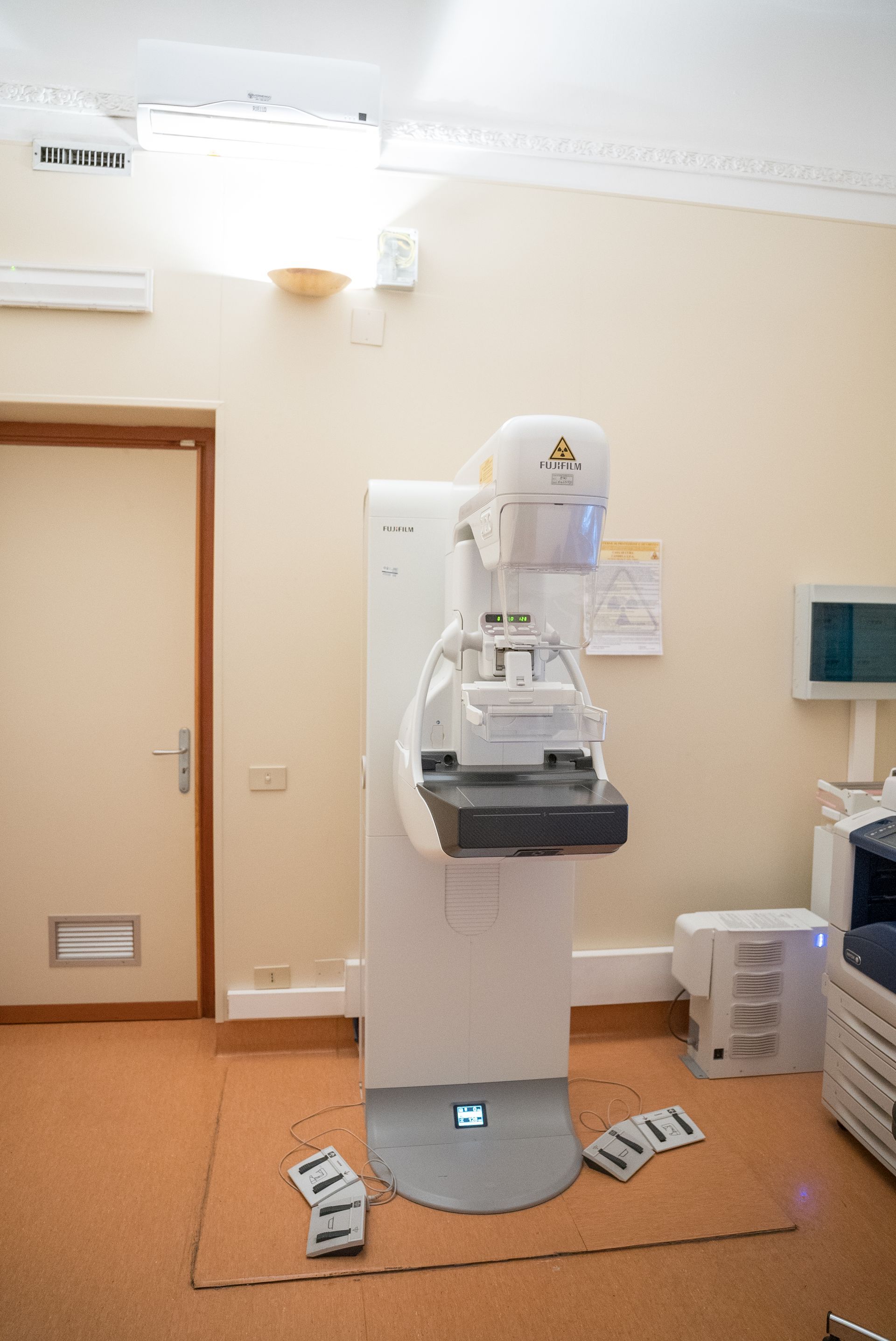 Un apparecchio per l'imaging del seno è posizionato in una stanza, accanto a una porta.