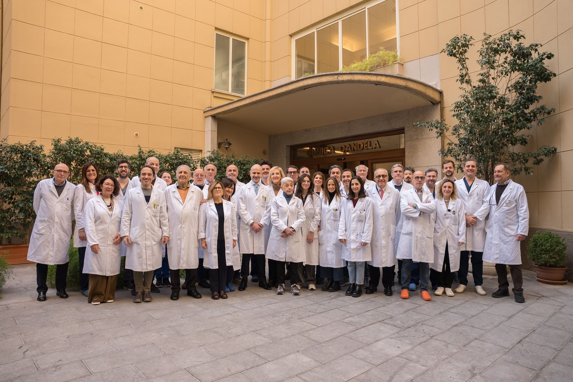 Un folto gruppo di medici e infermieri posa per una foto davanti a un edificio.