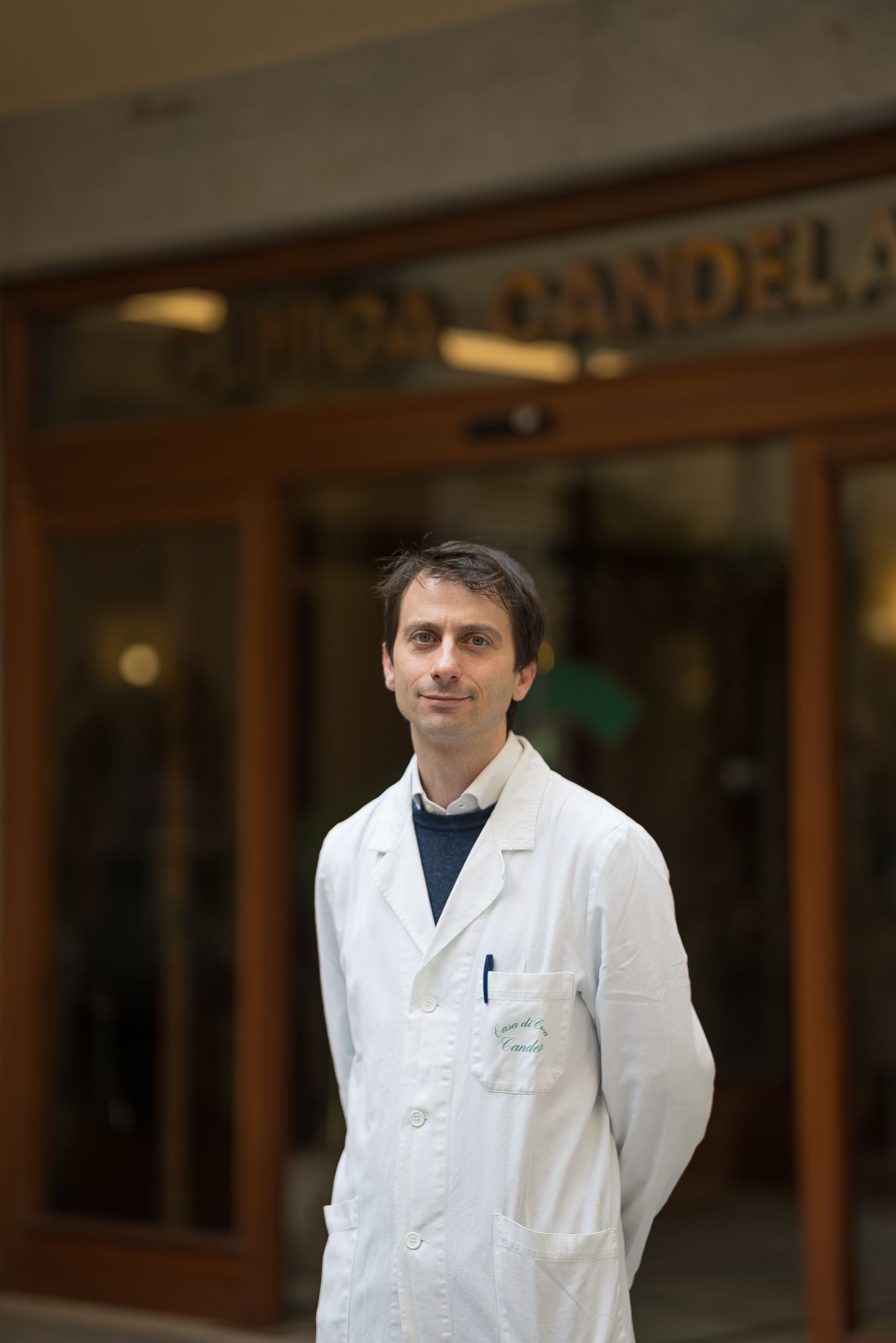 Un uomo in camice è in piedi davanti a un edificio.