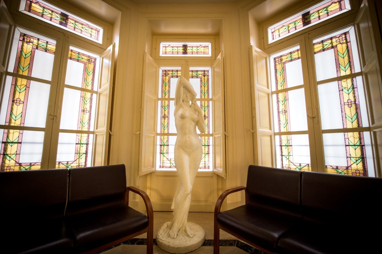 Una statua di una donna si trova in una stanza con vetrate colorate.