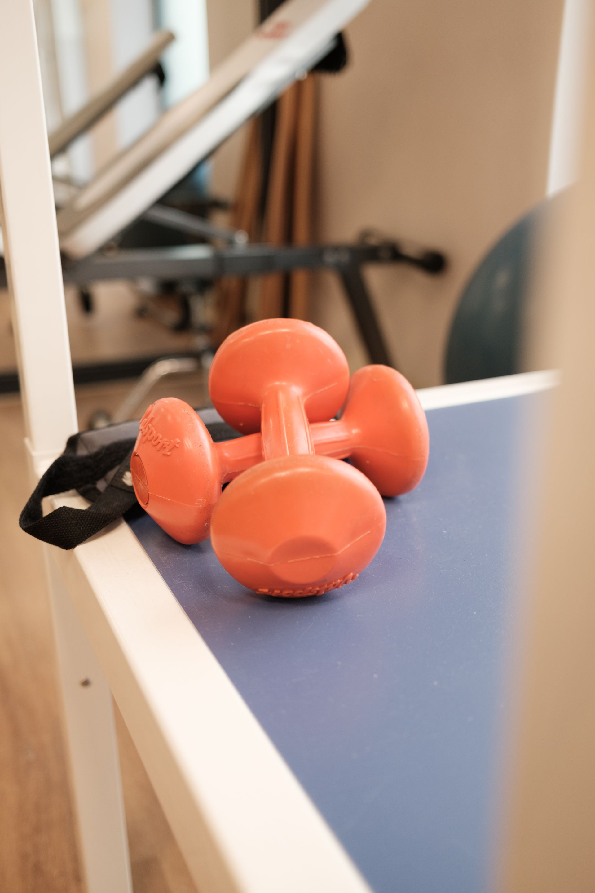 Due manubri arancioni sono appoggiati su un tavolo blu in una palestra.