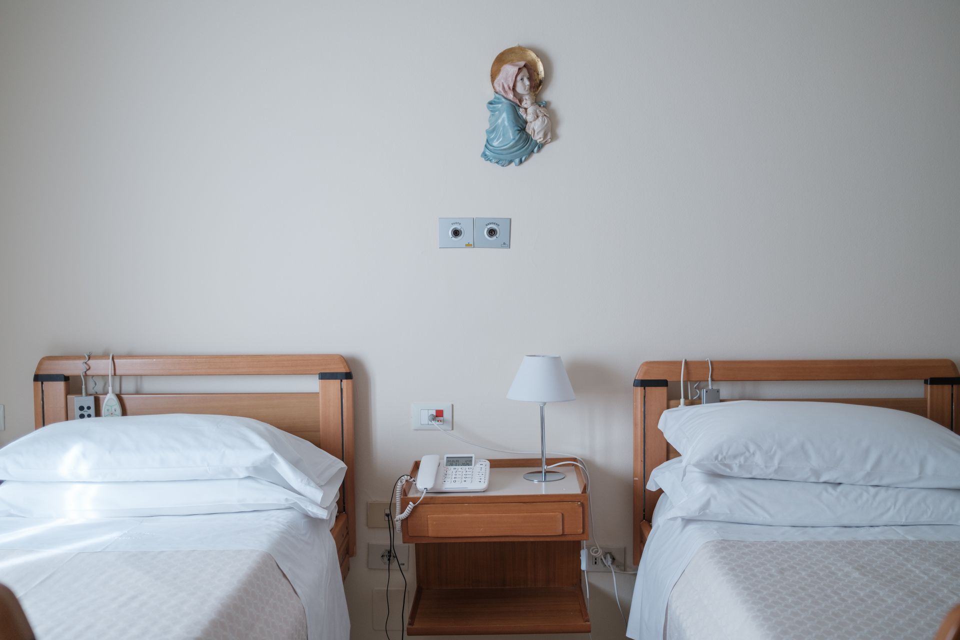 Una stanza d'ospedale con due letti e un comodino