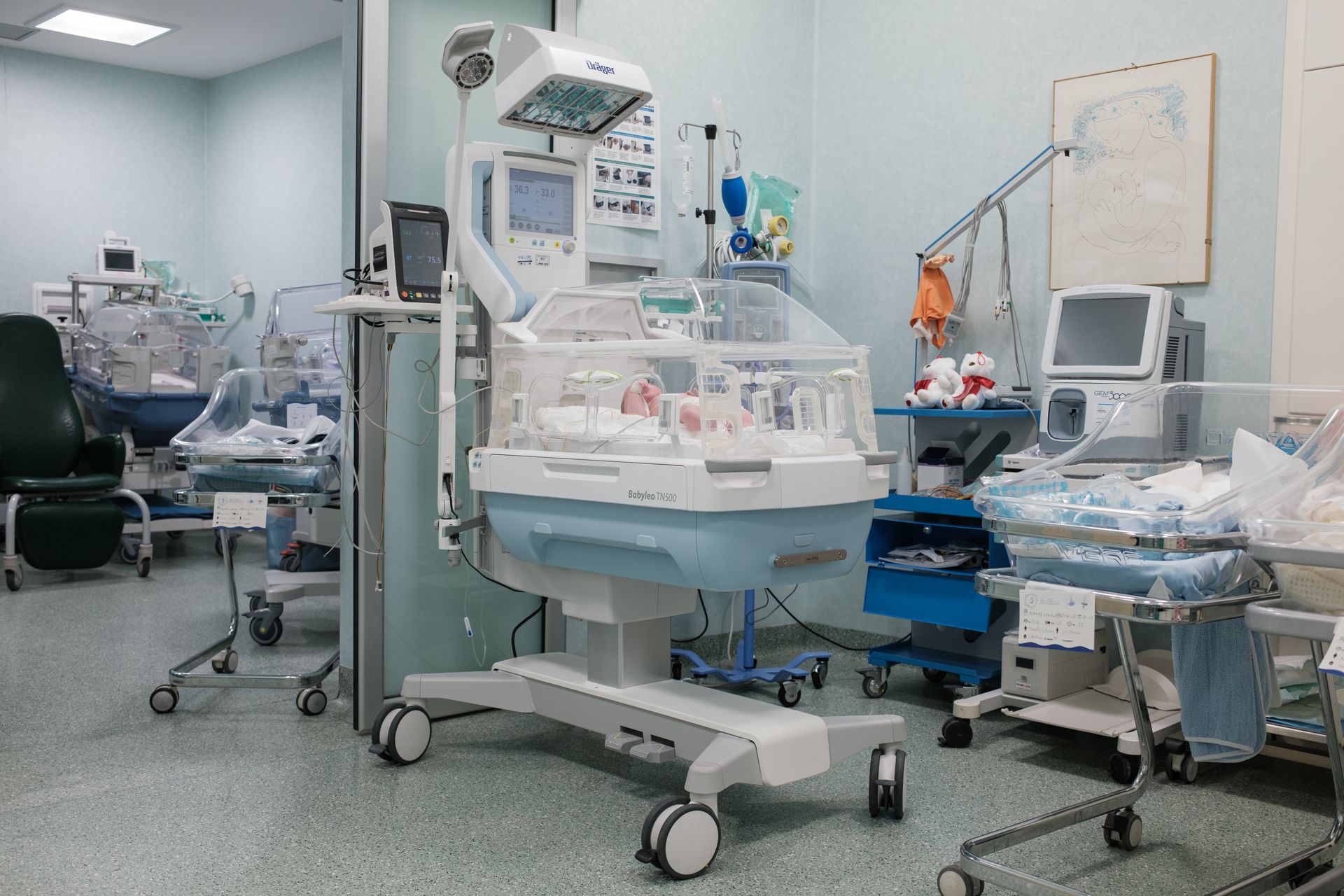 Una stanza d'ospedale piena di attrezzature mediche e di un'incubatrice per neonati.