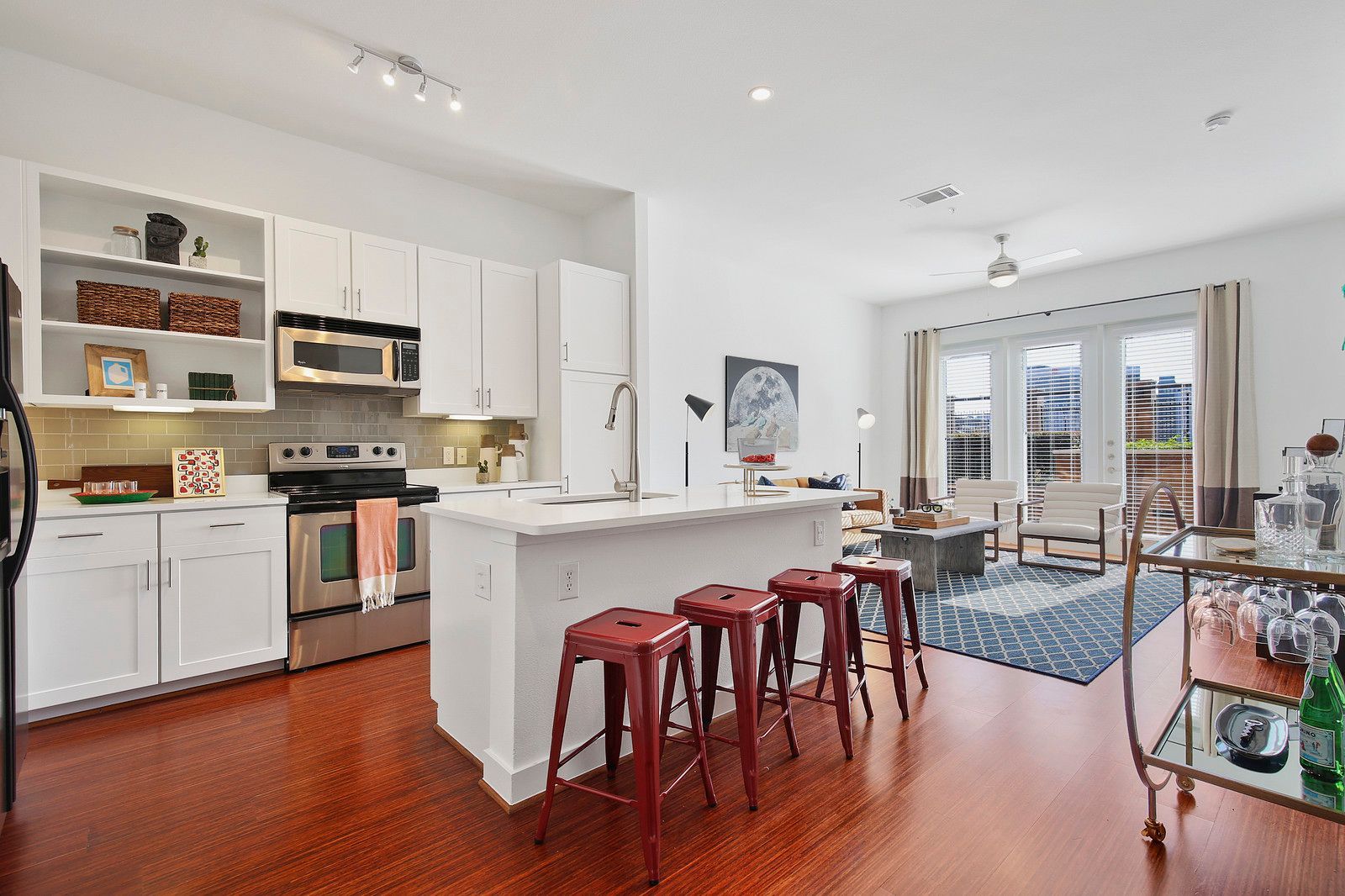 A kitchen with white cabinets and red stools