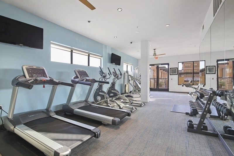 A gym with a lot of treadmills and a large mirror.