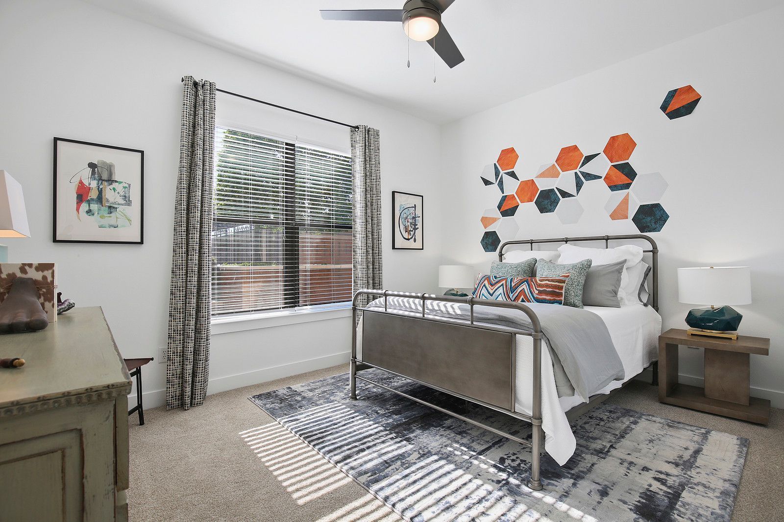 A bedroom with a bed , dresser , nightstand and ceiling fan.