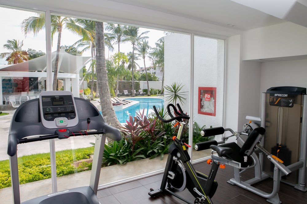 Sala de ejercicios de H2Otel by LD con equipos modernos y vista a la piscina, ideal para un entrenamiento revitalizante.