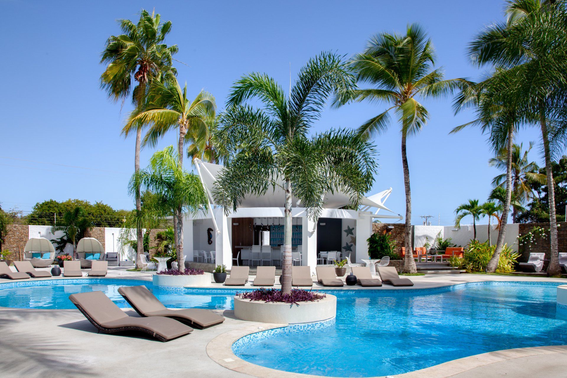 Bar en piscina de H2Otel by LD, oasis tropical con tumbonas y aguas cristalinas en Playa El Agua.