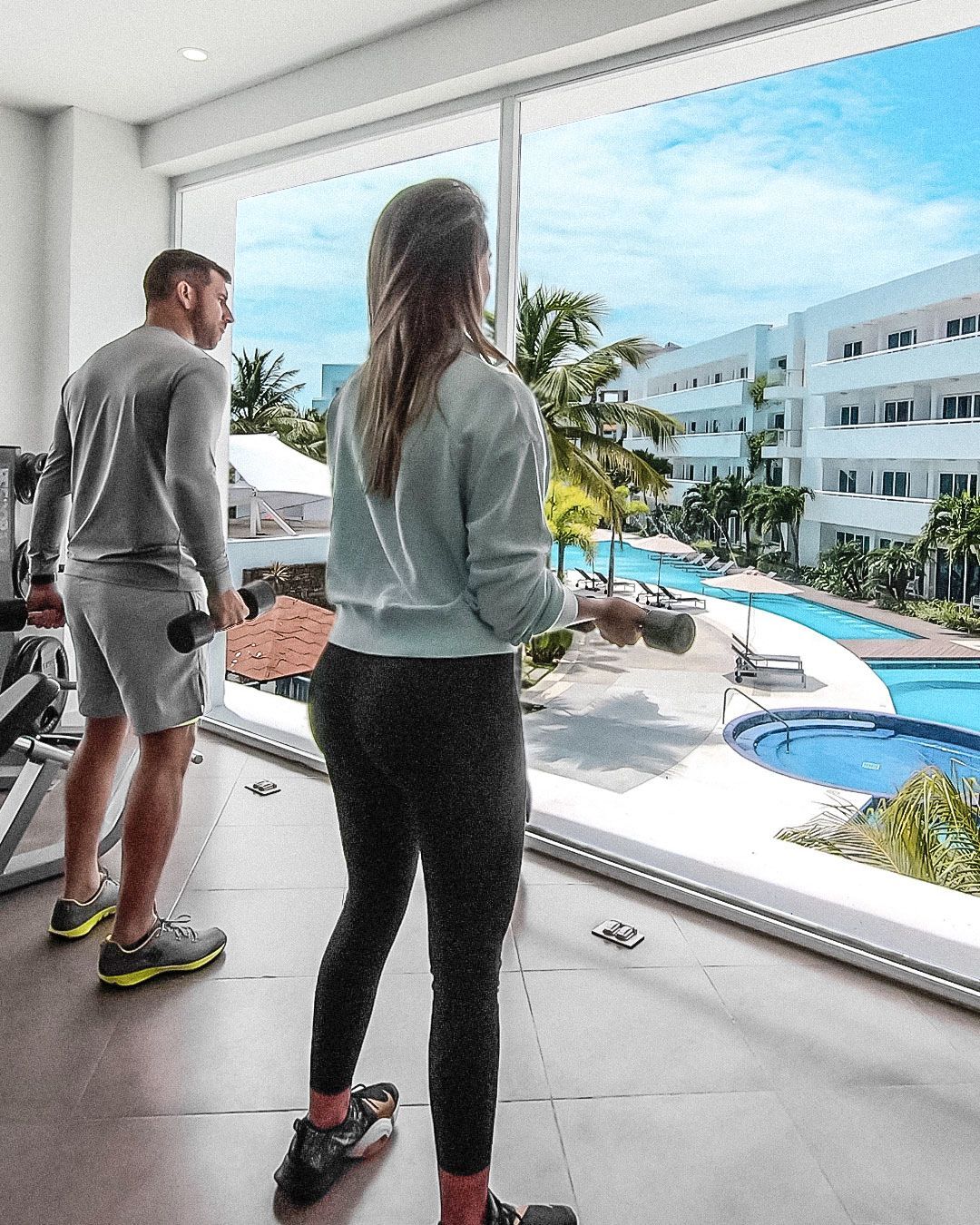 Sala de ejercicios en LD Plus, Playa El Agua, con vista a la piscina y equipo moderno para entrenar.