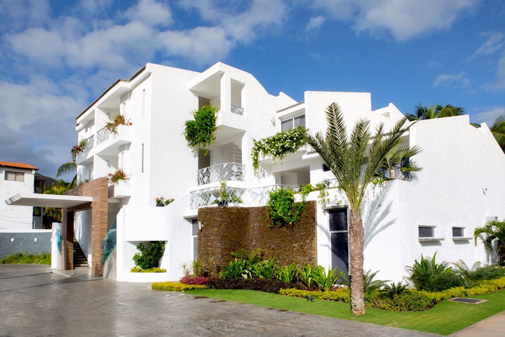 Fachada moderna del H2Otel By LD en Playa el Agua, con diseño contemporáneo y rodeado de vegetación tropical.