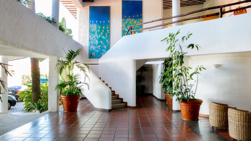 Lobby del Hotel LD Palm Beach en Playa El Agua, con escalera curva y decoración luminosa.