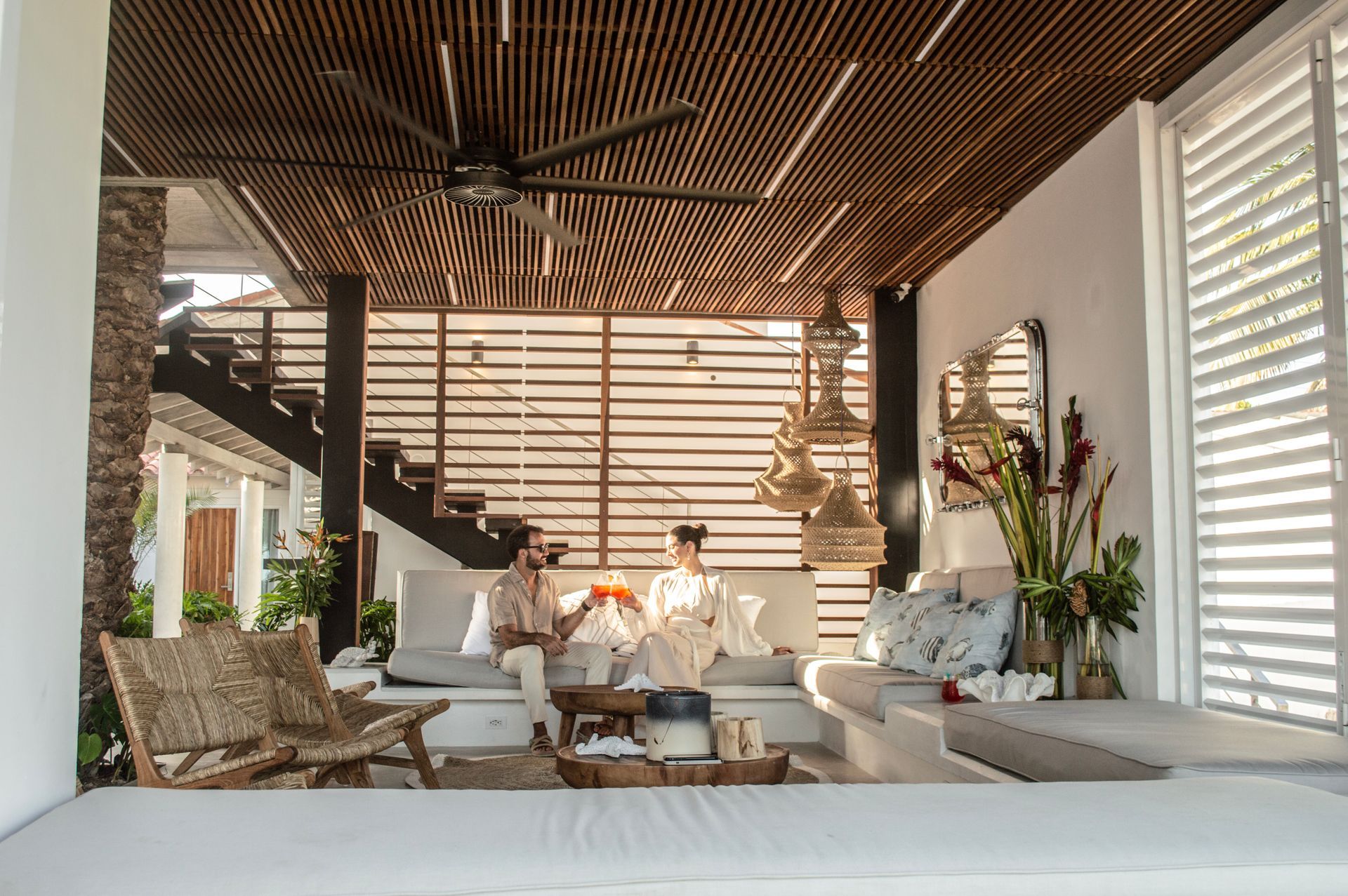Lobby moderno y tropical del Macanao Lodge By LD con sofás blancos, plantas decorativas y escalera de madera.
