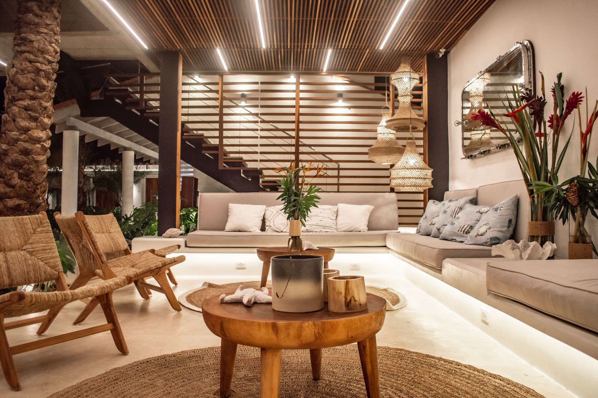 Lobby moderno y tropical del Macanao Lodge By LD con sofás blancos, plantas decorativas y escalera de madera.