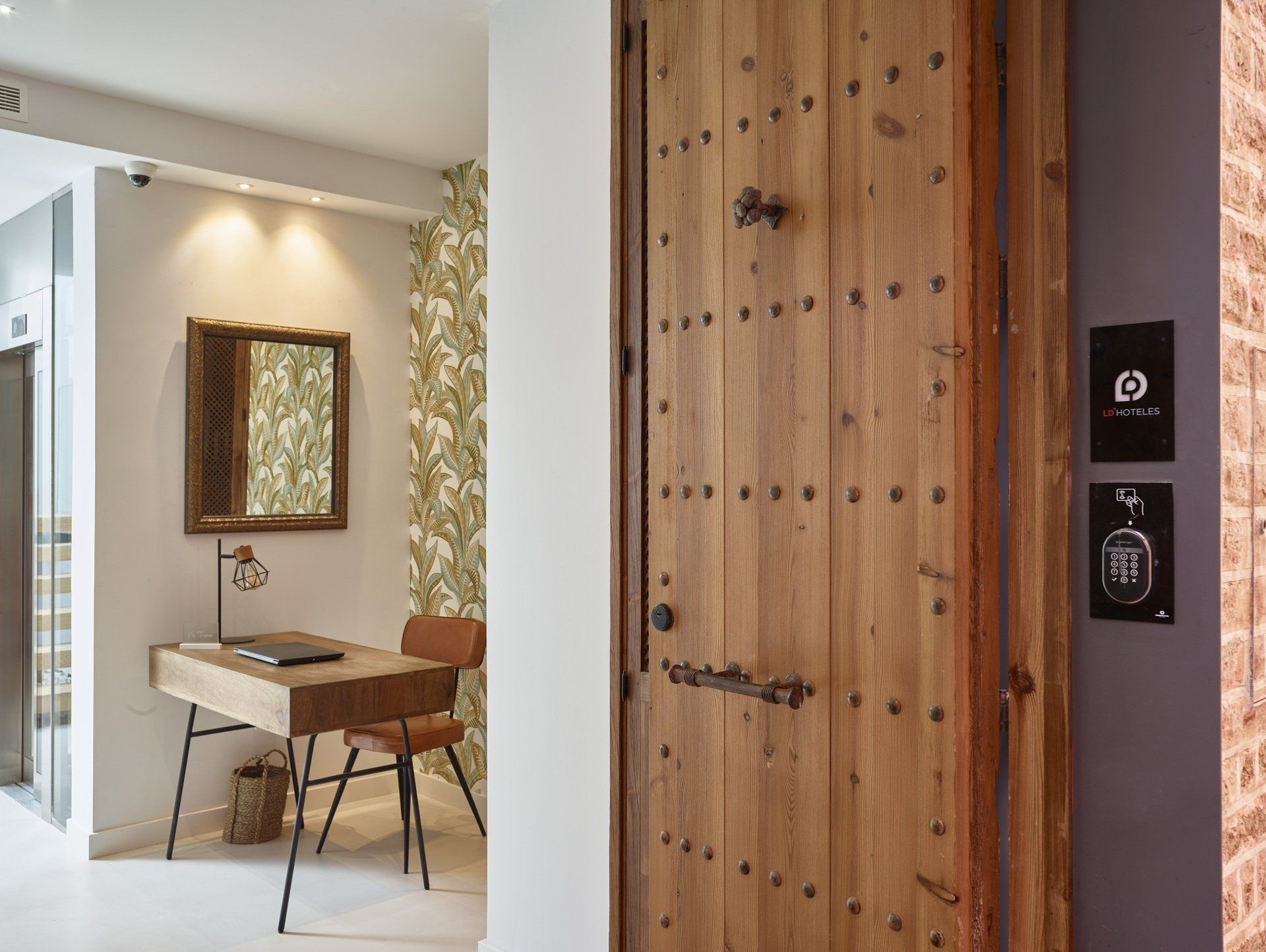 Recepción del hotel LD Convento Cister Málaga, con diseño rústico y moderno, puerta histórica y acceso electrónico.