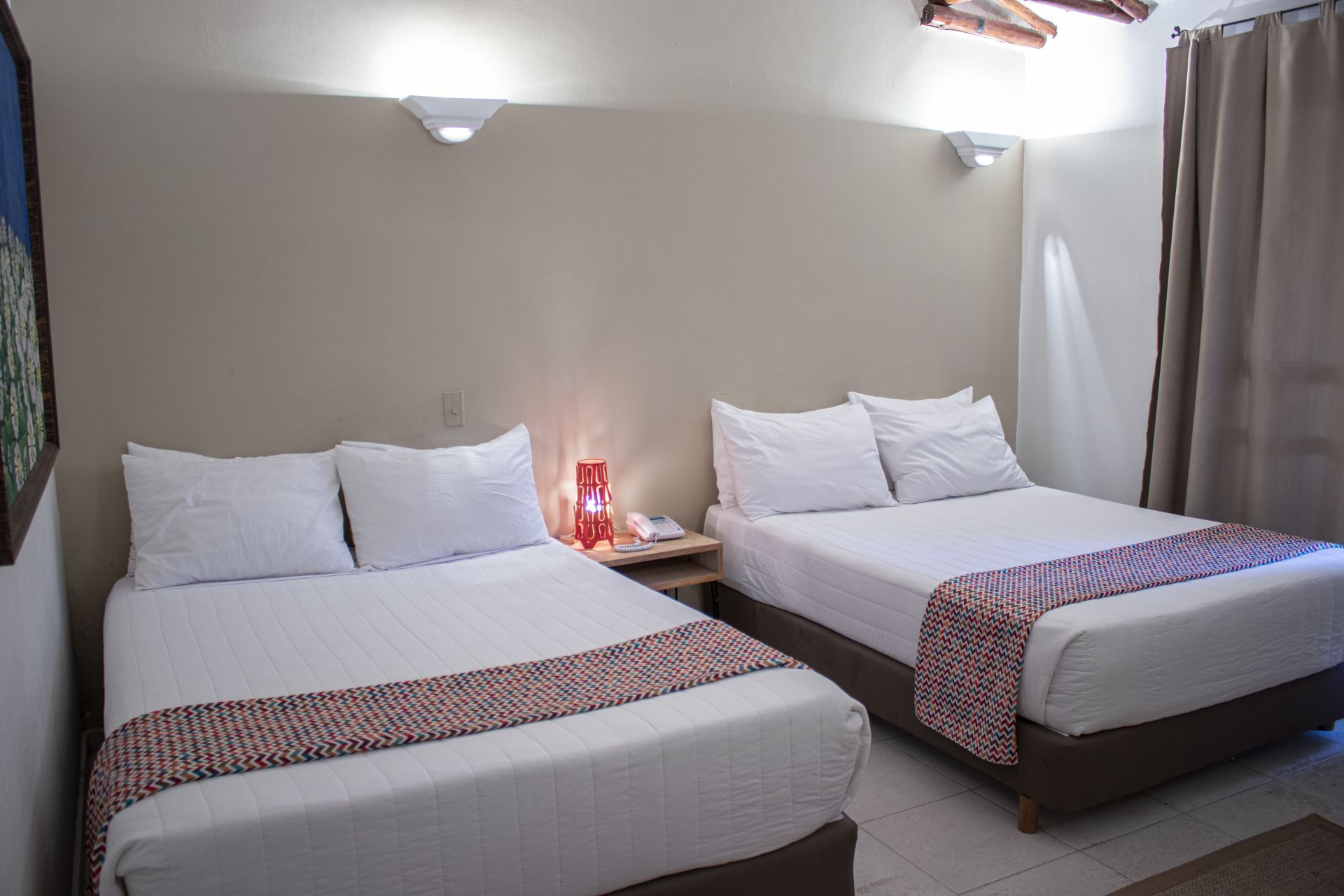 Habitación cuádruple en LD Palm Beach, Playa El Agua, con dos camas dobles y decoración cálida y moderna.