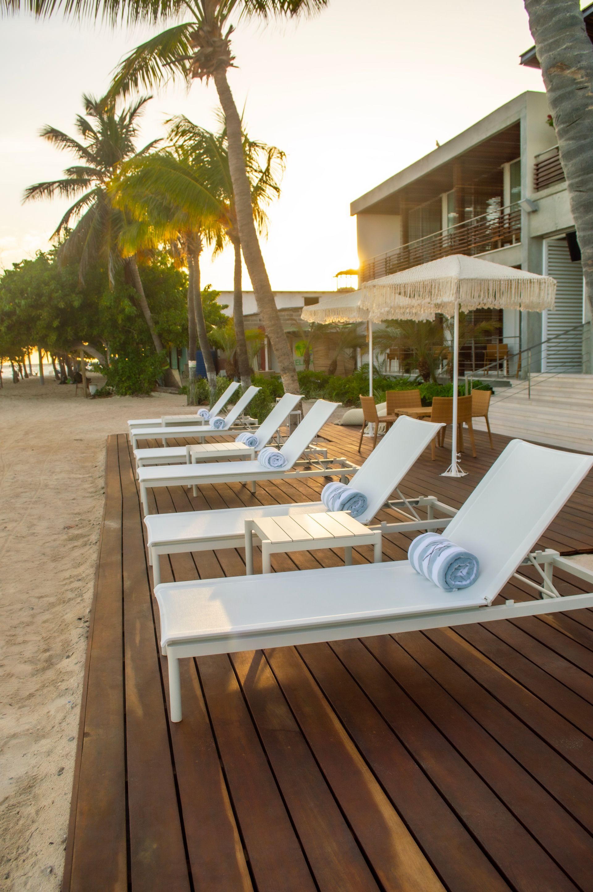 Tumbonas blancas con toallas en terraza de madera frente al mar en el Macanao Lodge, Los Roques.