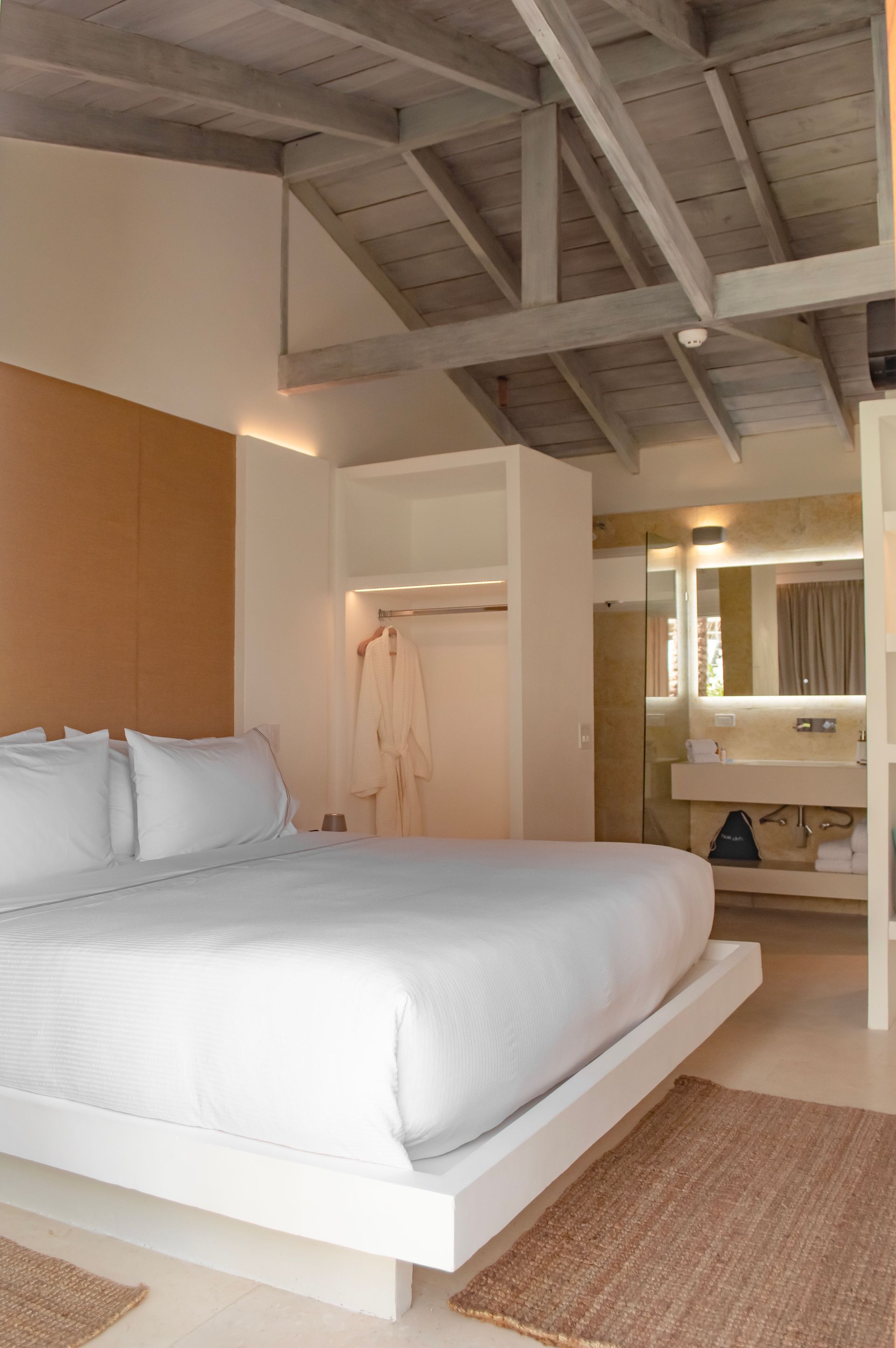 Habitación Deluxe King en Macanao Lodge, con cama grande, decoración elegante y baño abierto, para una estancia de lujo.