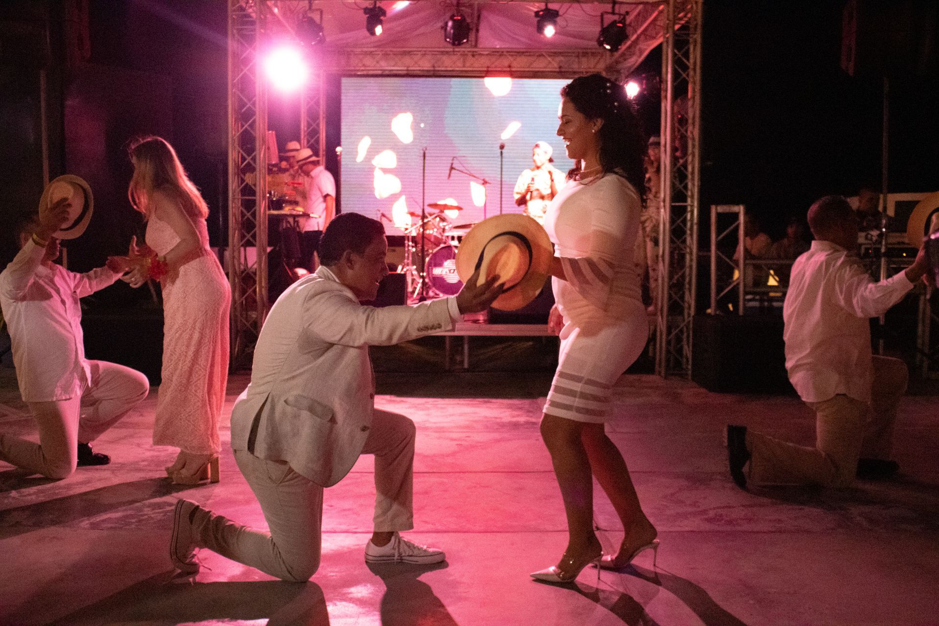 Fiesta vibrante en terraza LD Plus, Playa el Agua, con música en vivo y baile bajo luces coloridas.