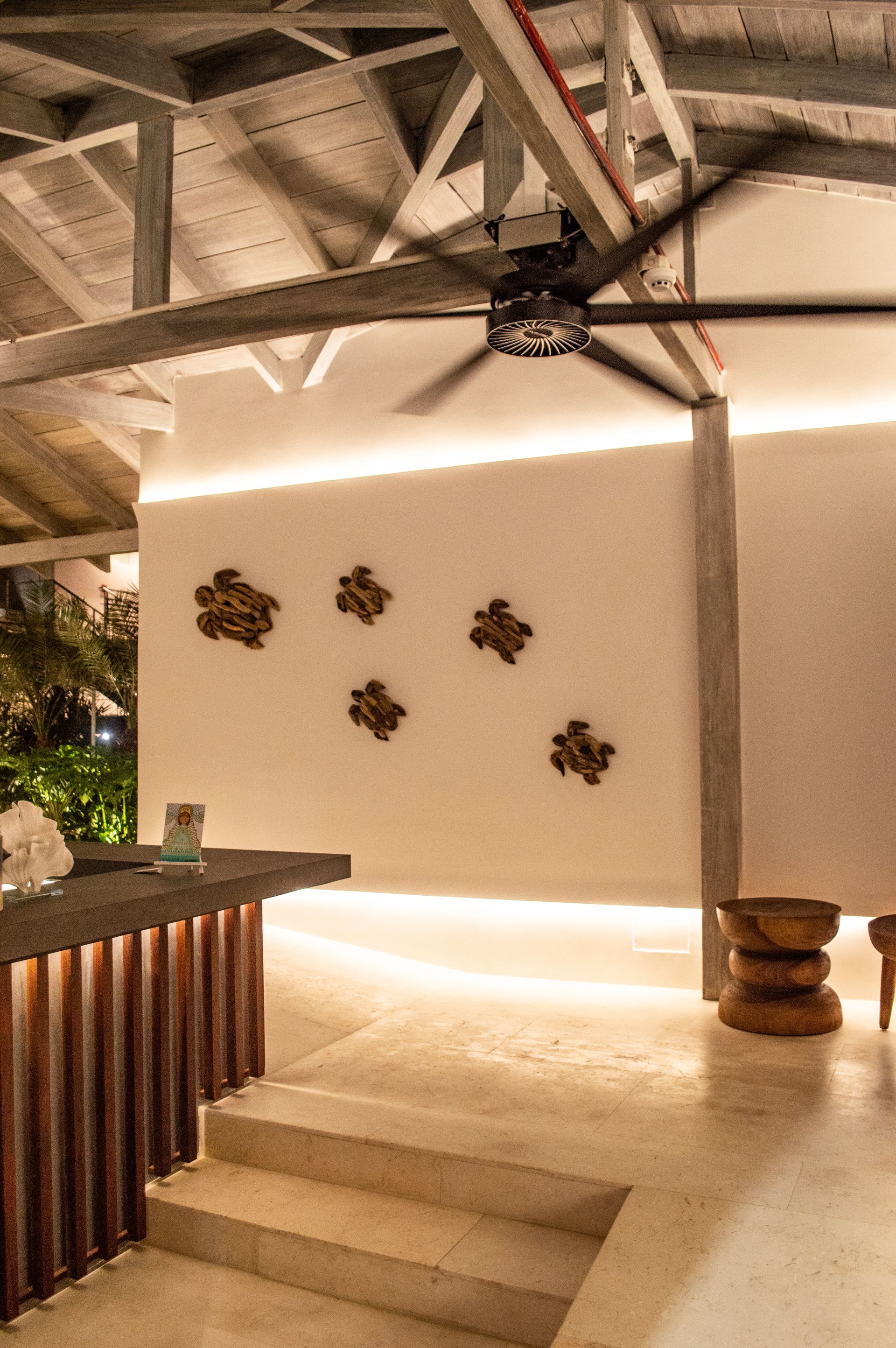 Lobby moderno y tropical del Macanao Lodge By LD con sofás blancos, plantas decorativas y escalera de madera.