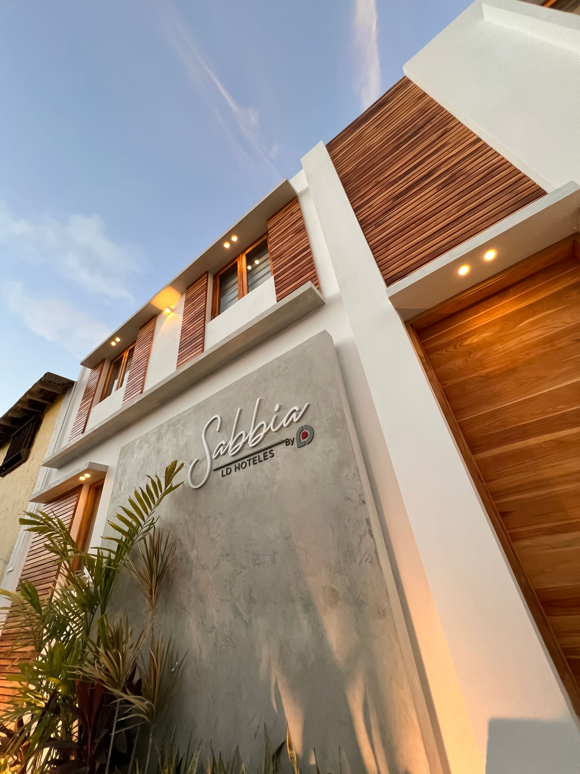 Fachada del Hotel Sabbia by LD Hoteles en Los Roques, con diseño moderno y elementos de madera y ladrillo.