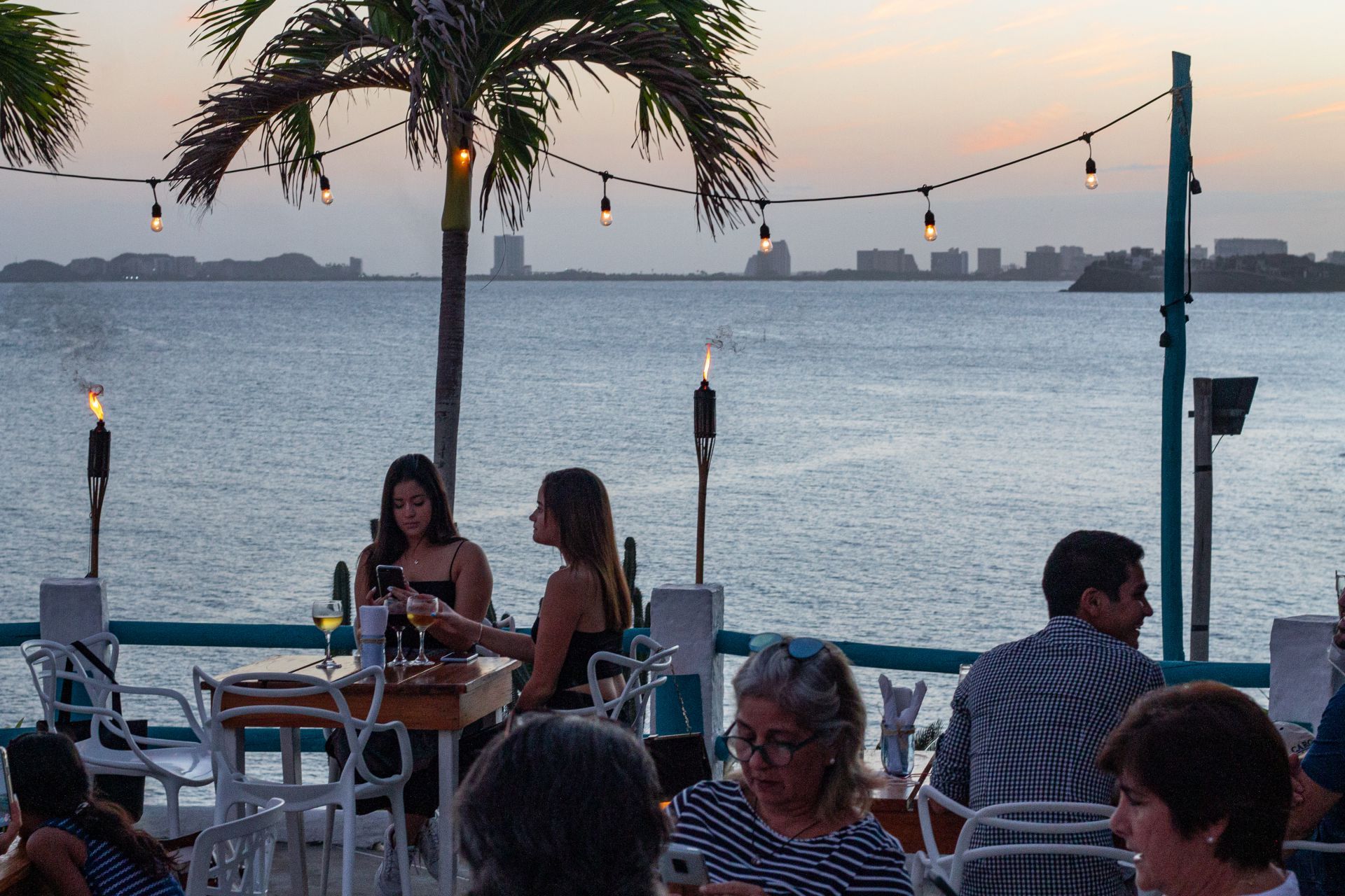 Restaurante Guayoyo en La Caranta, con iluminación acogedora al atardecer y vista al agua. Ideal para cenas al aire libre.