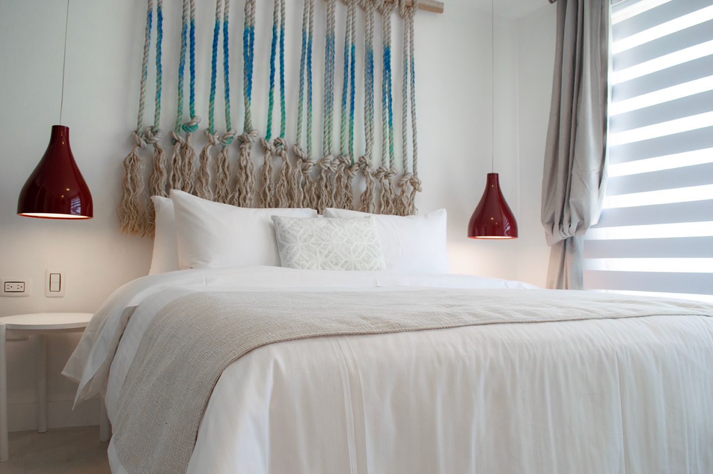 Habitación del Hotel Sabbia by LD Hoteles en Los Roques, con cama blanca, decoración inspirada en la playa y lámparas rojas.