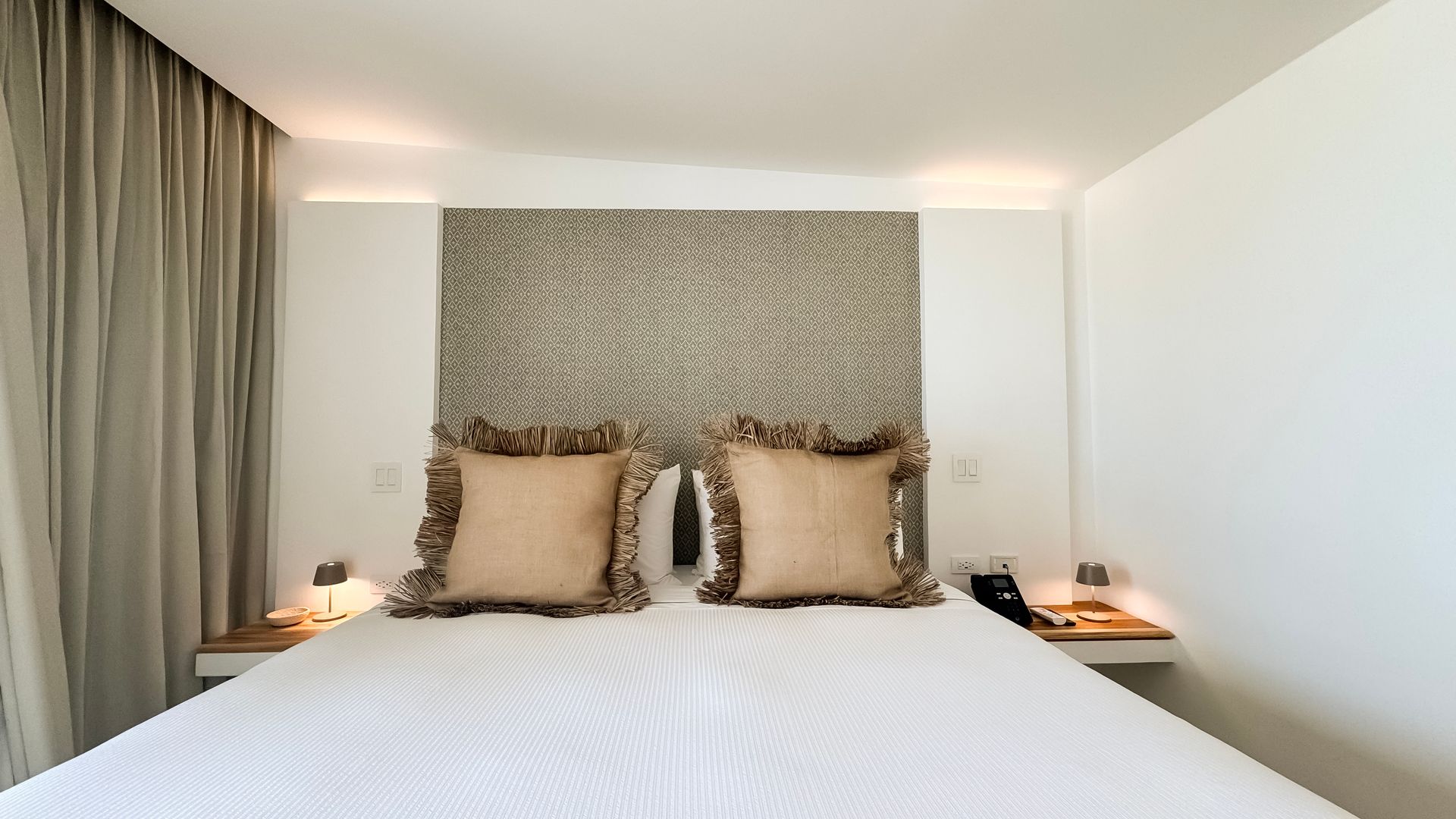 Habitación superior en Macanao Lodge con cama amplia, TV plana y balcón con vista al mar Caribe y vegetación tropical.