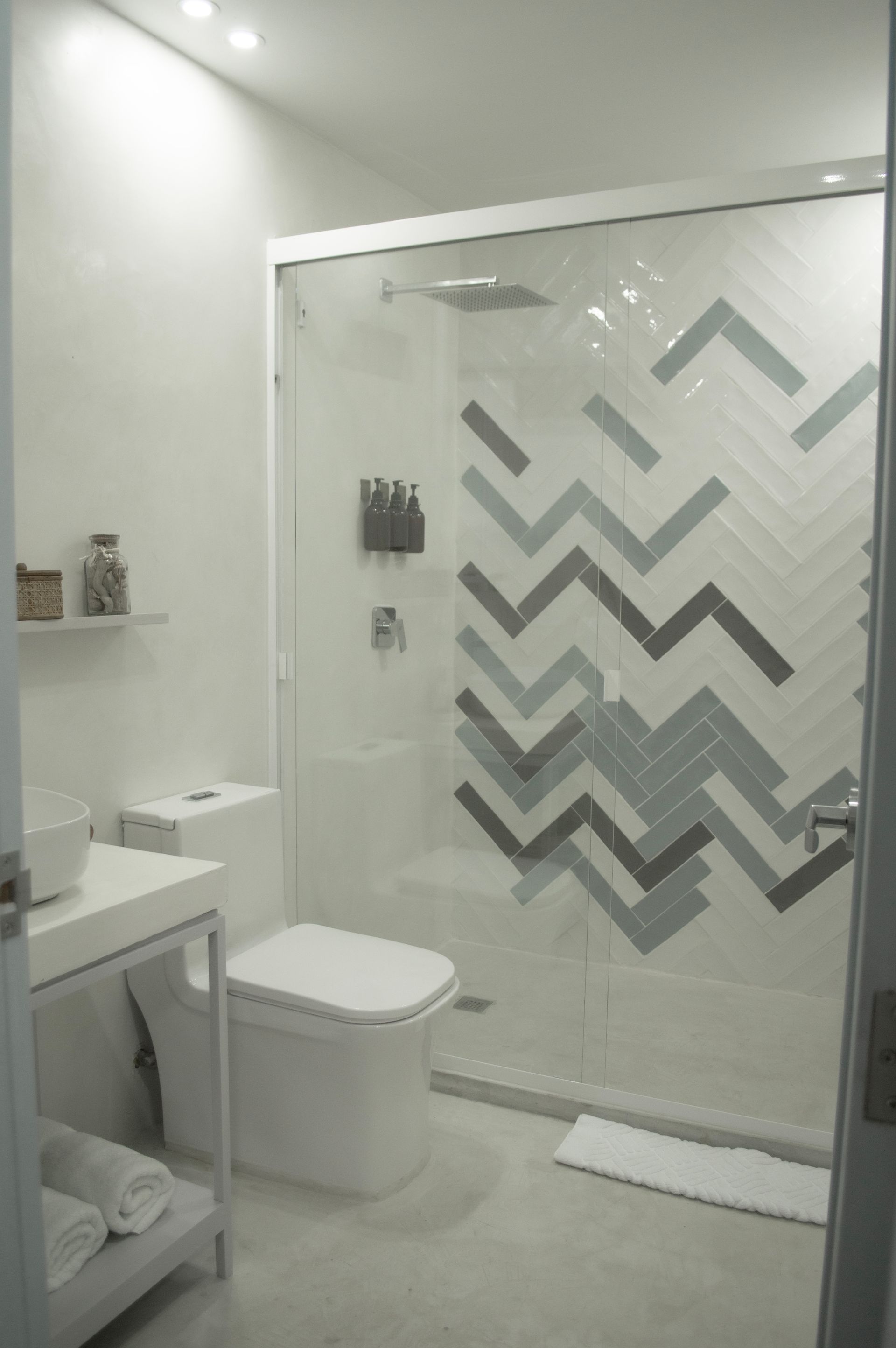 Baño moderno con lavabo, inodoro y ducha con patrones geométricos en azul y gris.