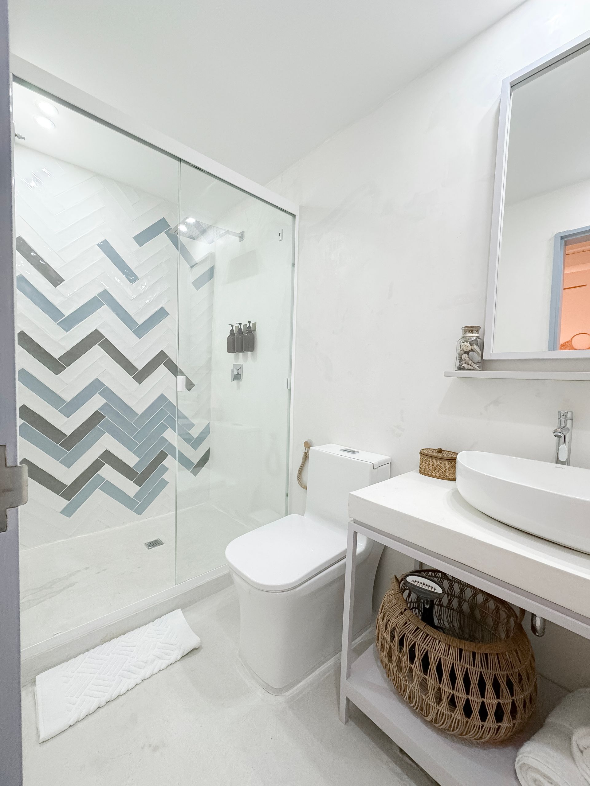 Baño moderno con lavabo de vasija, grifo de pared y ducha con puertas de vidrio.